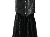une robe noire avec une chemise rose et un gilet, suspendue à un cintre
