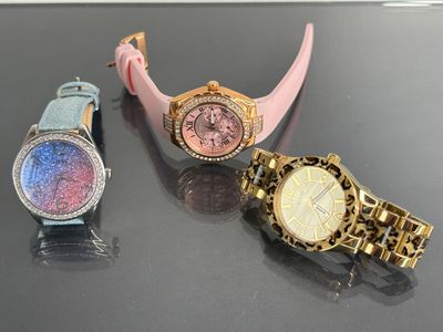 three different colored watches sitting on a black surface next to each other