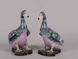 pair of colorfully painted ceramic ducks sitting on top of a wooden base