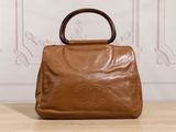 brown leather handbag with bamboo handle on wooden table