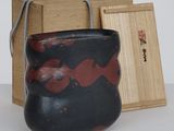 a black and red vase sitting next to a wooden box
