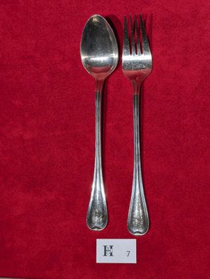 deux cuillères en argent et une fourchette posées sur une nappe rouge