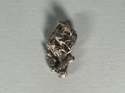 une petite figurine en argent représentant une femme assise sur une branche d'arbre