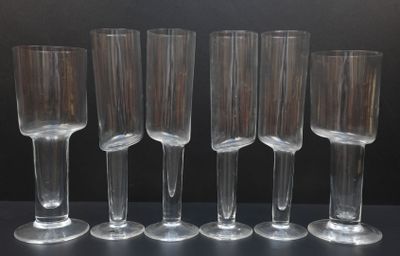 six verres à vin transparents alignés en rang sur une table