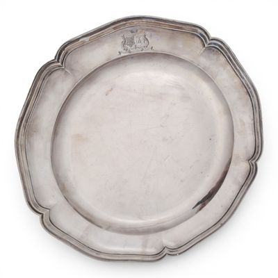 an antique silver plate on a white background with a crest on the edge
