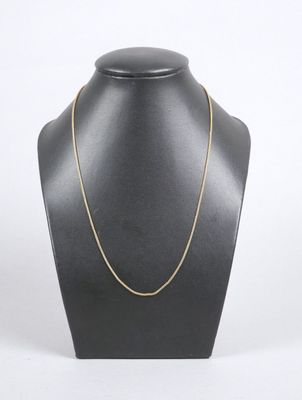 a gold chain necklace on a mannequin neck