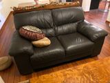 a black leather couch with pillows on it in a living room