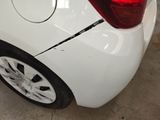 the rear end of a white car with a broken tire