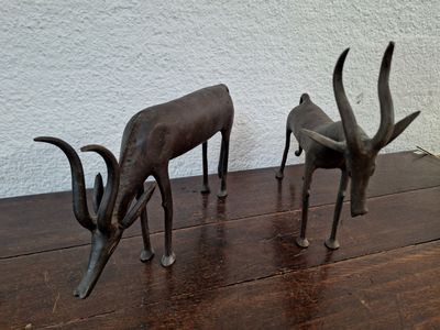 two statues of antelope standing on a wooden table