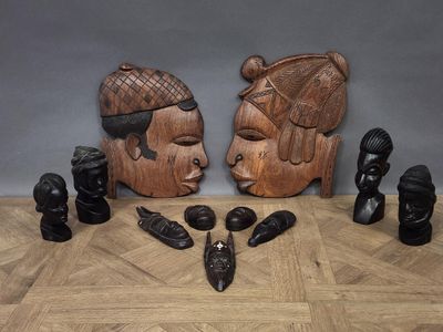 wooden sculptures of two faces and a woman ' s head on a wooden floor