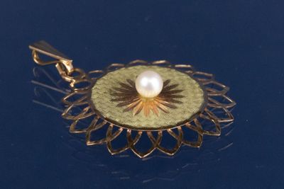un pendentif en or serti d'une perle, sur un fond bleu