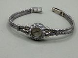 bracelet en argent orné d'une montre, posé sur un fond blanc