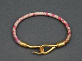 a close up of a pink and gold bracelet with a hook