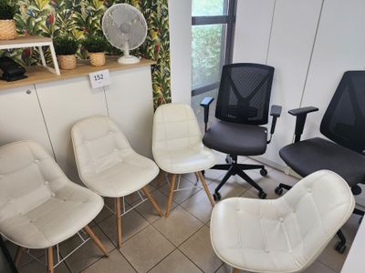 quatre chaises dans une pièce, avec un ventilateur en arrière-plan