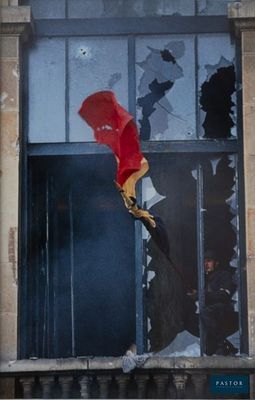 une fenêtre cassée à laquelle est suspendu un parapluie rouge