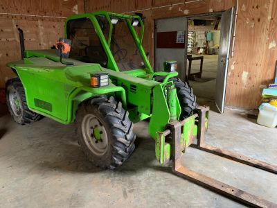 a green tractor that is parked inside of a building
