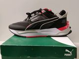 une paire de baskets noires et rouges posée sur une boîte verte