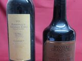 two bottles of wine sitting next to each other on a red cloth