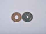 two gears on a white surface one has a hole and the other has a hole