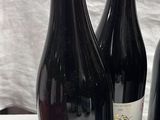 Trois bouteilles de vin sont posées sur une table recouverte d'une nappe blanche.