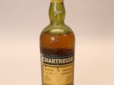 une vieille bouteille de whisky Chartreuse posée sur une surface blanche