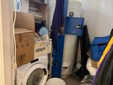 une machine à laver et un sèche-linge dans une pièce où il y a beaucoup de cartons par terre