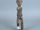 une vieille figurine représentant un homme debout, les mains sur les hanches