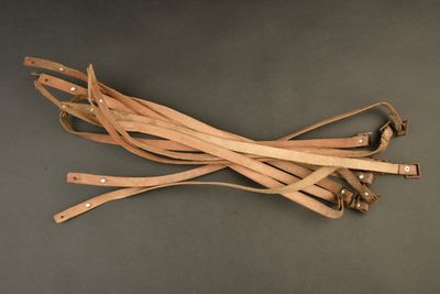 several leather straps on a gray surface with one strap tied to the other