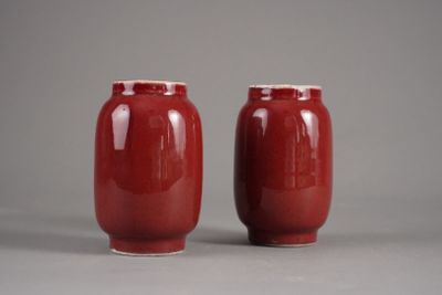 une paire de vases rouges posés sur une surface grise