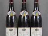 Trois bouteilles de vin sont alignées sur une table en verre