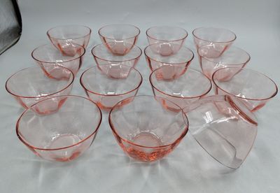 twelve pink depression glasses on a white tablecloth