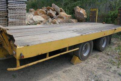 un camion à plateau jaune garé à côté d'un tas de pierres