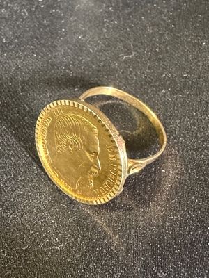 une bague en or surmontée d'une pièce de monnaie