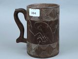 une vieille tasse marron décorée d'un motif, posée sur une table