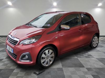 une voiture rouge est garée dans une pièce au sol en damier