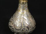 a silver and gold vase sitting on a black surface