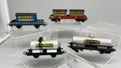 quatre petits trains miniatures exposés dans des boîtes transparentes posées sur une table