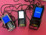 trois téléphones portables posés les uns à côté des autres sur une surface rose