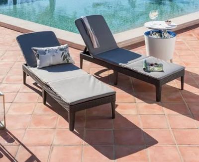 deux chaises longues et une table près d'une piscine