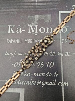 un bracelet en chaîne d'or orné de diamants posé sur une carte de visite