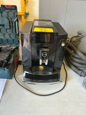 une machine à café posée sur un plan de travail, à côté d'une boîte à outils