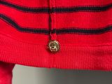 a close up of a red sweater with a button on it