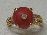 une photo d'une bague sertie d'une pierre rouge et d'un diamant