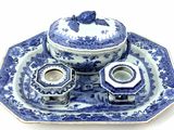 a blue and white plate with a bowl and a candle holder on it