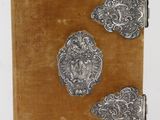 un vieux livre orné de décorations métalliques argentées, posé sur une table