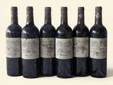 six bouteilles de vin sont alignées sur une surface blanche