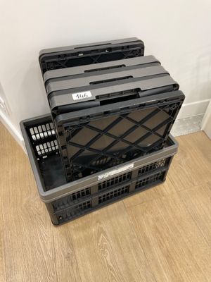 three black plastic crates stacked on top of each other on a wooden floor