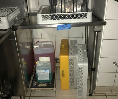 un chat assis dans une cage posée sur une étagère dans une cuisine