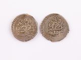 two silver coins with arabic writing on them on a white surface