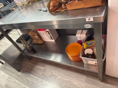 une table en acier inoxydable sur laquelle sont disposés tout un tas de plats